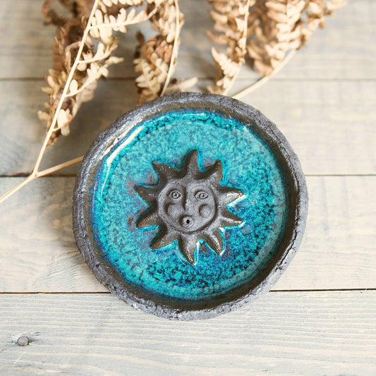 Handmade ceramic incense holder featuring the sun design. Crafted from black grogged clay and covered with blue glaze.