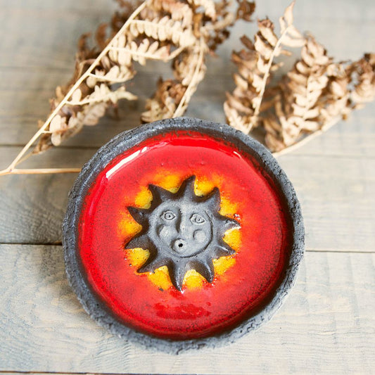 Handmade ceramic incense holder featuring the sun design. Crafted from black grogged clay and covered with red glaze.