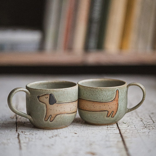 Handmade green ceramic mug with a matte glaze, featuring an unglazed dog design on the side.