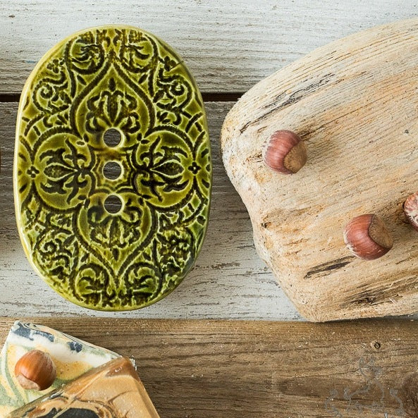 Handmade ceramic oval soap dish. Crafted from white clay and finished with a glossy green glaze. Designed with drainage holes, a concave shape, and four little feet.