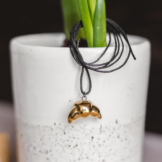 Handmade ceramic croissant pendant necklace with gold plated finish on black cord