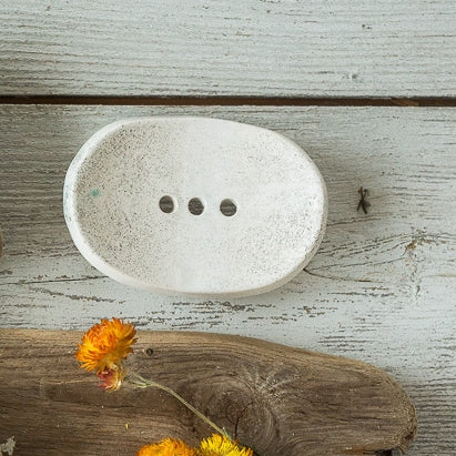 Handmade ceramic soap dish. Crafted from white clay and finished with a mat dotted glaze. Designed with drainage holes, a concave shape, and four little feet.