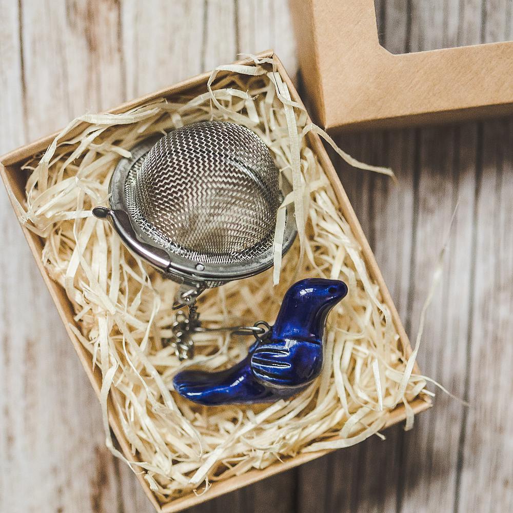 Tea infuser with ceramic blue bird hanging from the chain. Packed in a paper gift box.