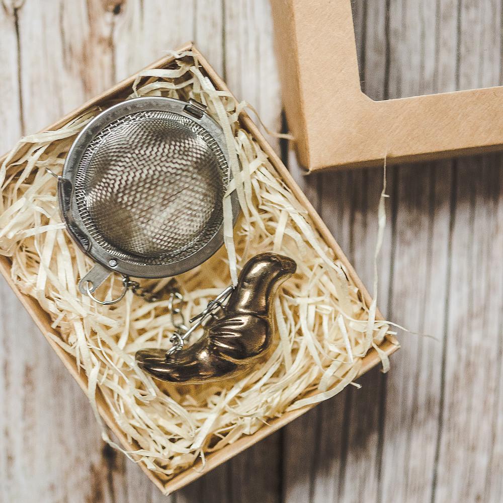 Tea infuser with ceramic bronze bird hanging from the chain. Packed in a paper gift box.