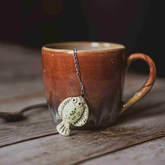 tea infuser with ceramic green flatfish hanging from the chain