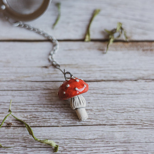 Tea infuser with red mushroom hanging from the chain.