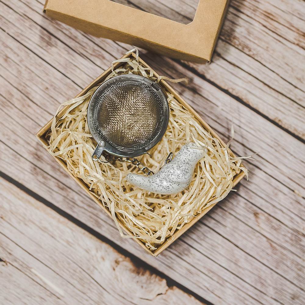 Tea infuser with ceramic white bird hanging from the chain. Packed in a paper gift box.