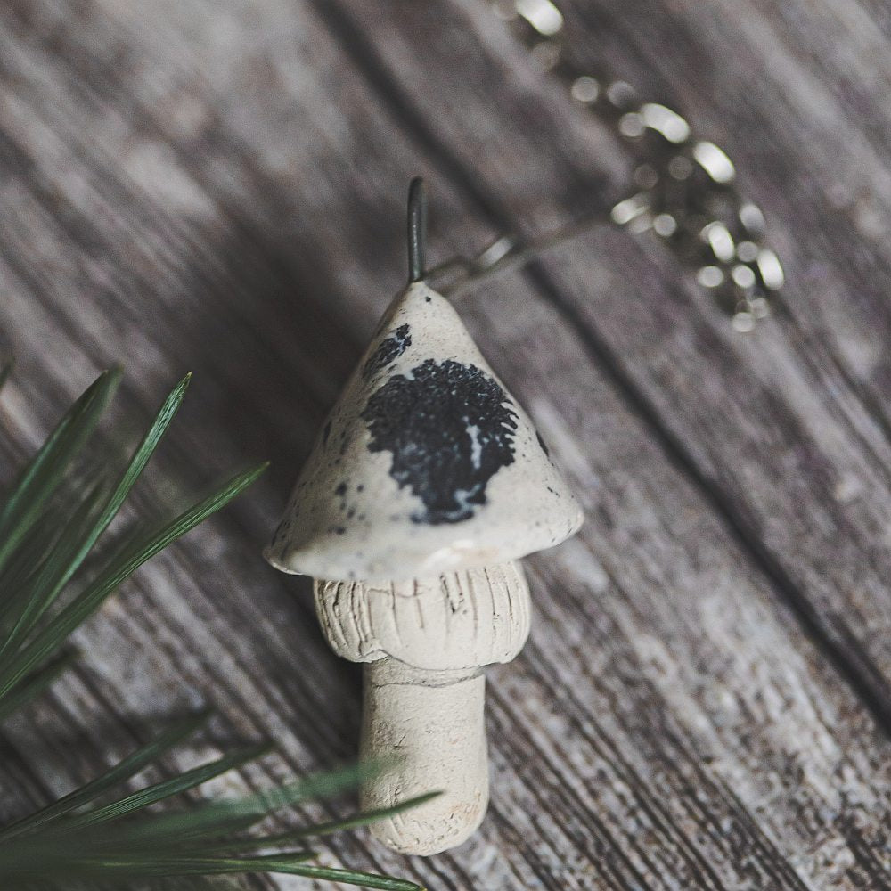 Tea infuser with ceramic white dotted mushroom hanging from the chain.