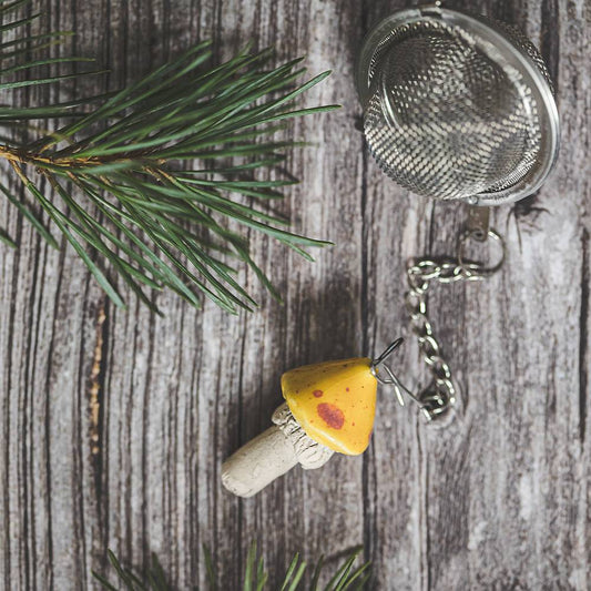 Tea infuser with ceramic yellow dotted mushroom hanging from the chain.