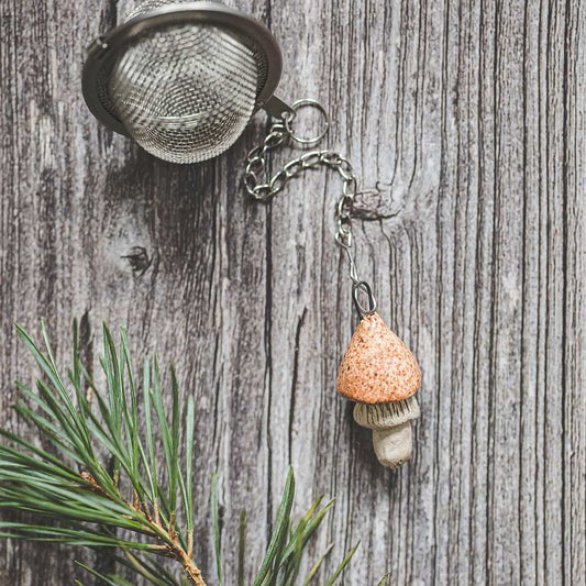 Tea infuser with ceramic yellowish mushroom hanging from the chain.