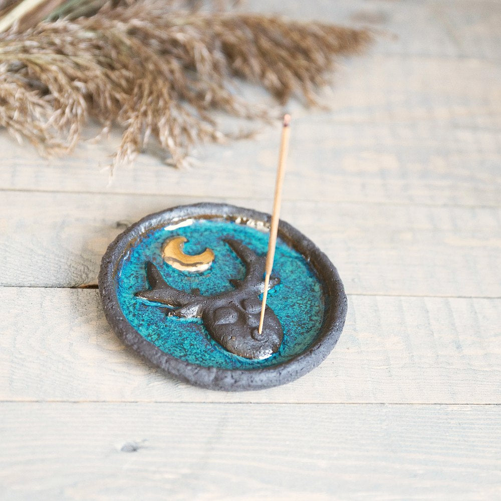 Handmade ceramic incense holder featuring mystic creature and gold plated moon design. Crafted from black grogged clay and covered with blue glaze.
