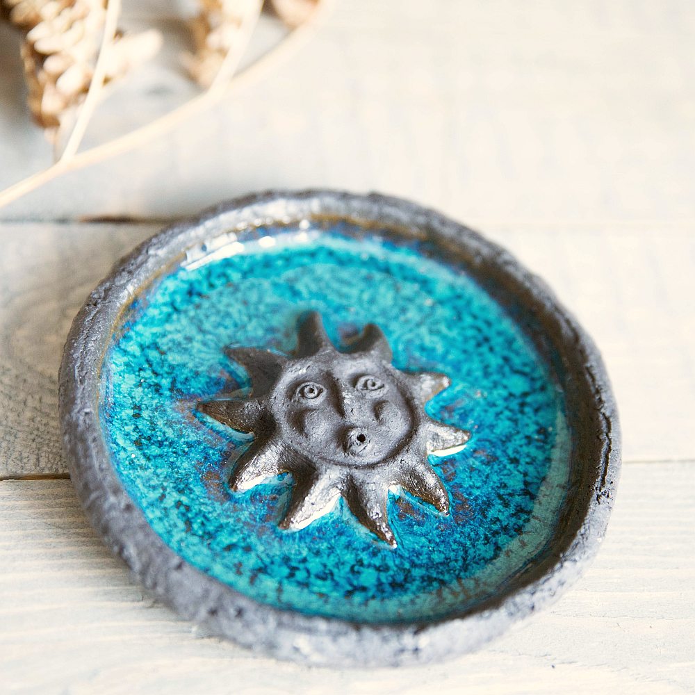 Handmade ceramic incense holder featuring the sun design. Crafted from black grogged clay and covered with blue glaze.