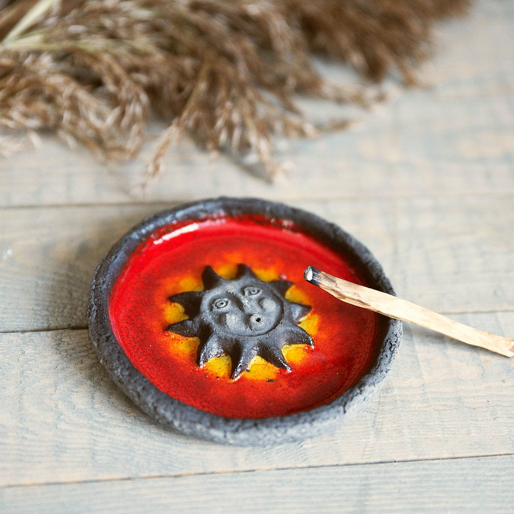 Handmade ceramic incense holder featuring the sun design. Crafted from black grogged clay and covered with red glaze.