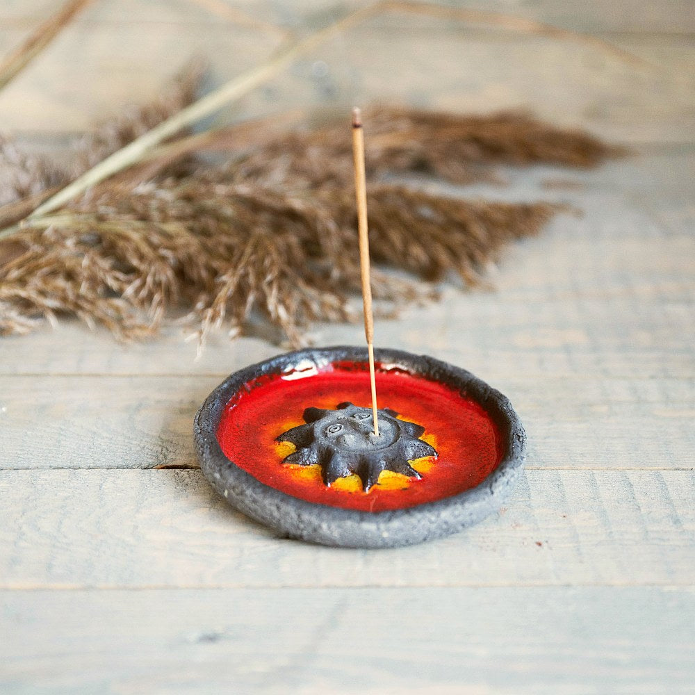 Handmade ceramic incense holder featuring the sun design. Crafted from black grogged clay and covered with red glaze.