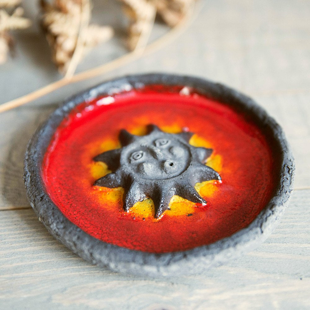 Handmade ceramic incense holder featuring the sun design. Crafted from black grogged clay and covered with red glaze.
