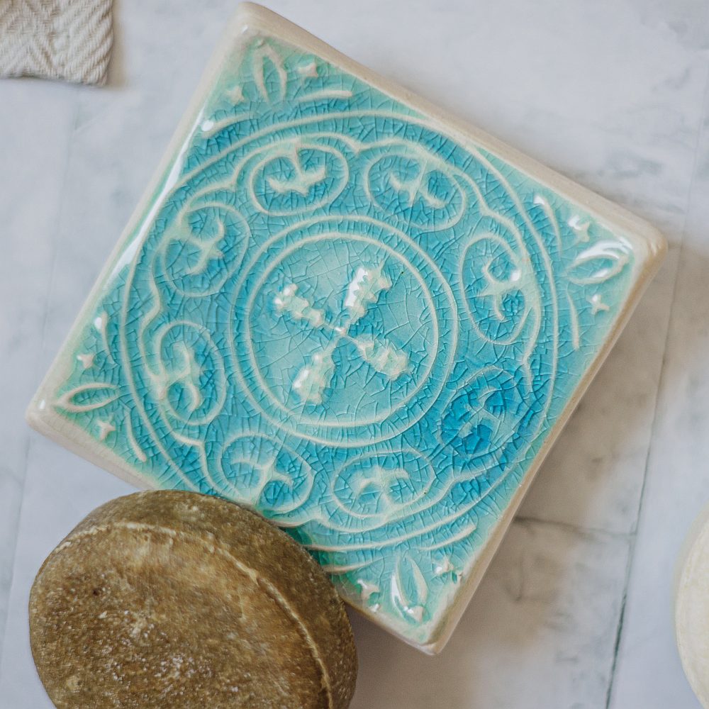 Handmade ceramic square soap dish. Crafted from white clay and finished with a glossy blue glaze. Designed with drainage holes, a concave shape, and four little feet.