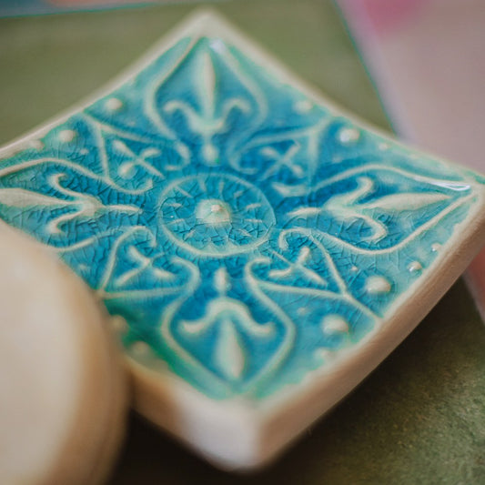 Handmade ceramic square soap dish. Crafted from white clay and finished with a glossy blue glaze. Designed with drainage holes, a concave shape, and four little feet.