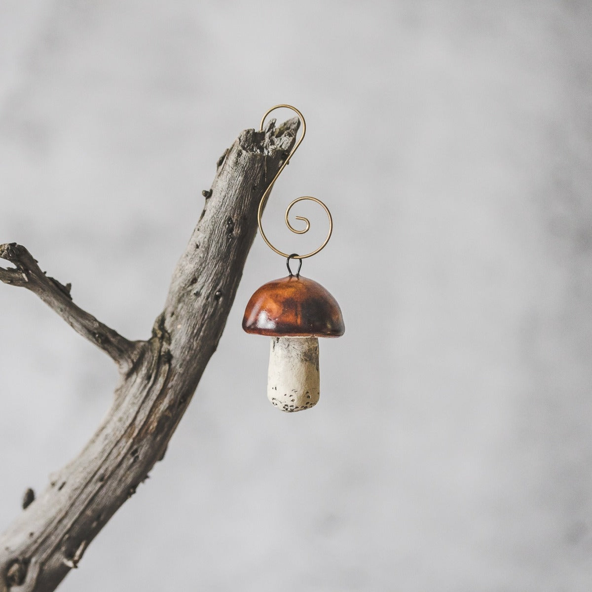 Boletus ceramic mushroom ornament hanging on a branch of Christmas tree.