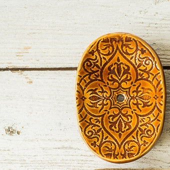 Handmade ceramic oval soap dish. Crafted from white clay and finished with a glossy brown glaze. Designed with drainage holes, a concave shape, and four little feet.