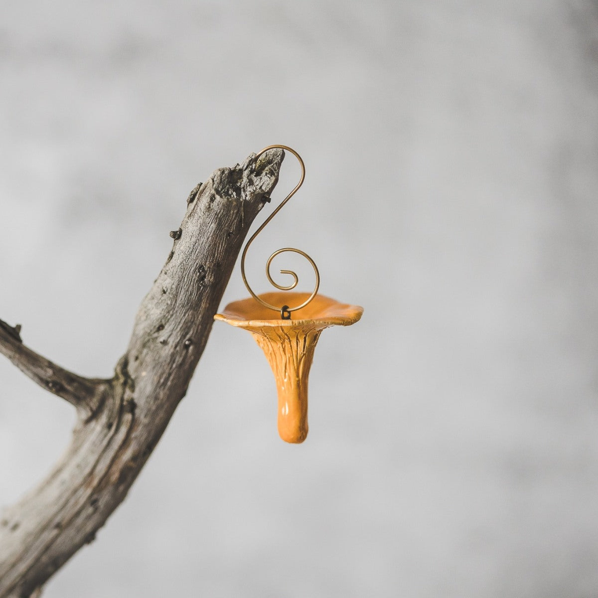 Chanterelle ceramic mushroom ornament hanging on a branch of Christmas tree.