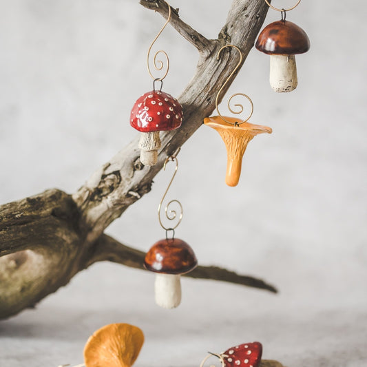 Christmas ornament set of 6 mushrooms: boletus, amanita and chanterelle. Hanging on a branch of Christmas tree.