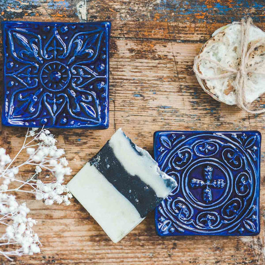 Handmade ceramic square soap dish. Crafted from white clay and finished with a glossy dark blue glaze. Designed with drainage holes, a concave shape, and four little feet.