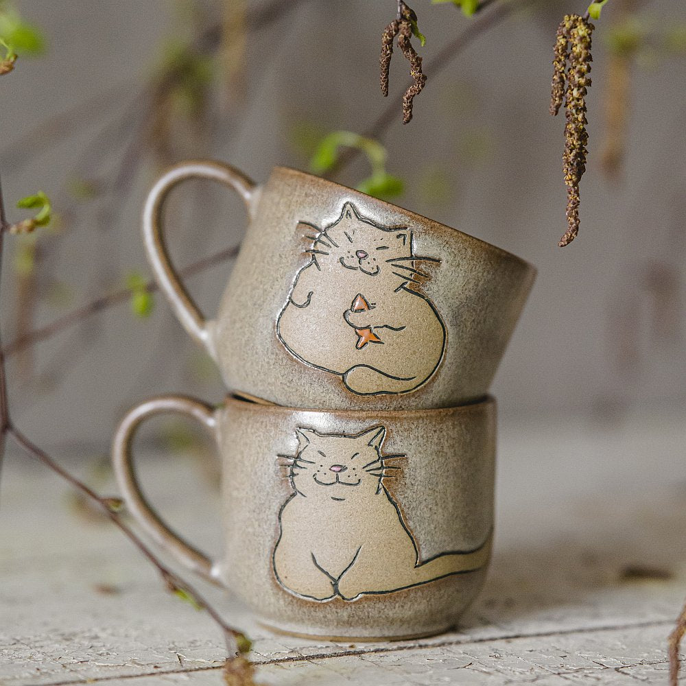 Handmade green ceramic mug with a matt glaze, featuring an unglazed cat design on the side.