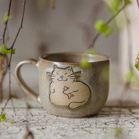 Handmade green ceramic mug with a matt glaze, featuring an unglazed cat design on the side.