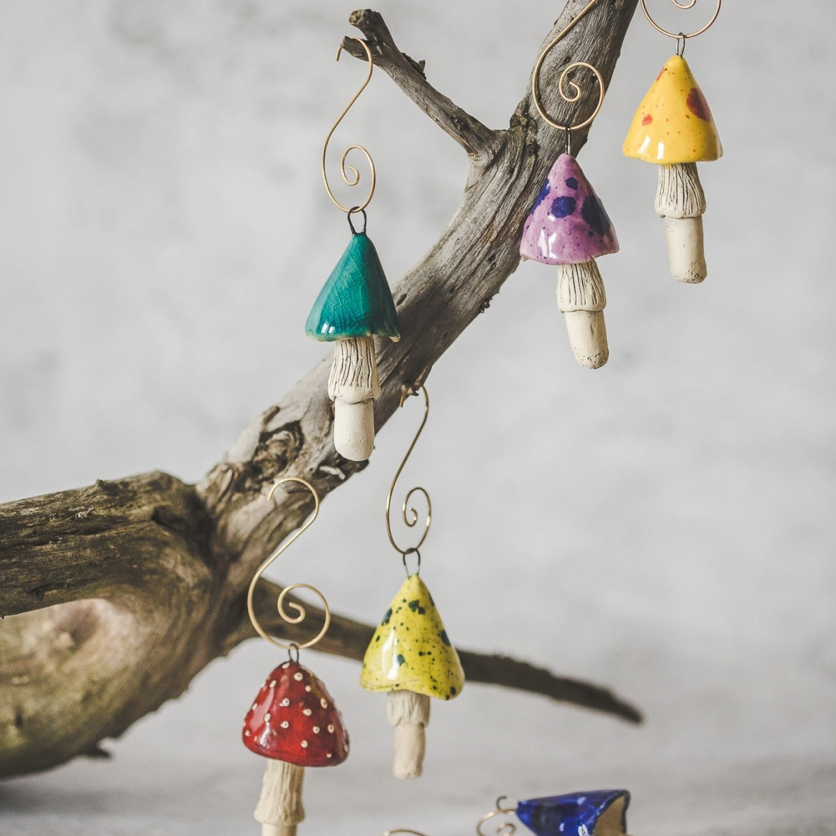 Christmas ornament set of 6 mushrooms: red, yellow, blue, purple. Hanging on a Christmas tree.
