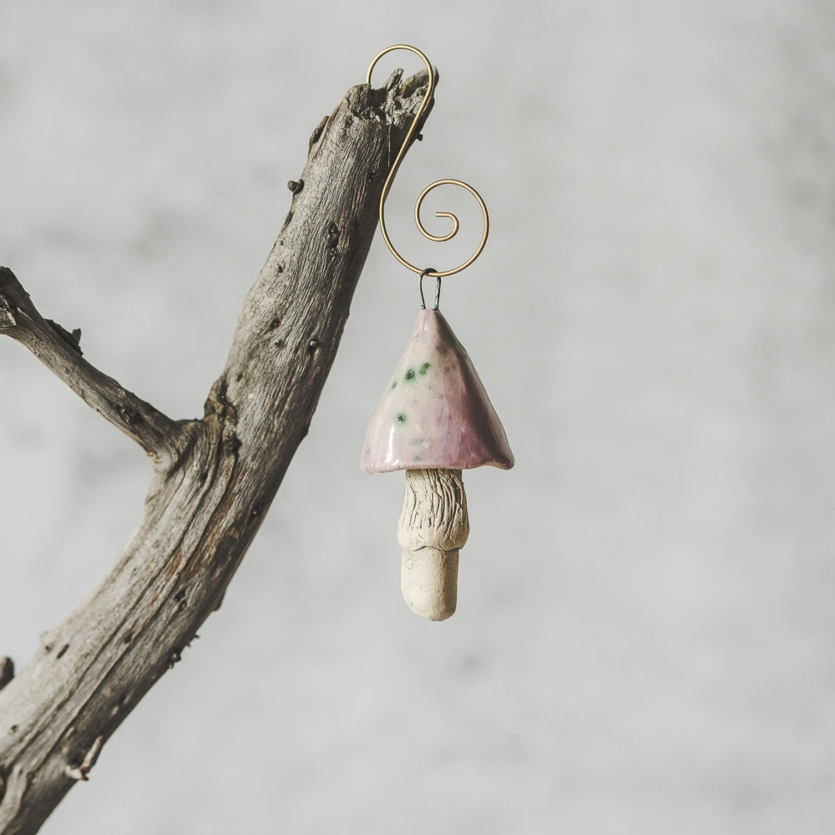 Ceramic magic swamp mushroom ornament hanging on a branch of Christmas tree.