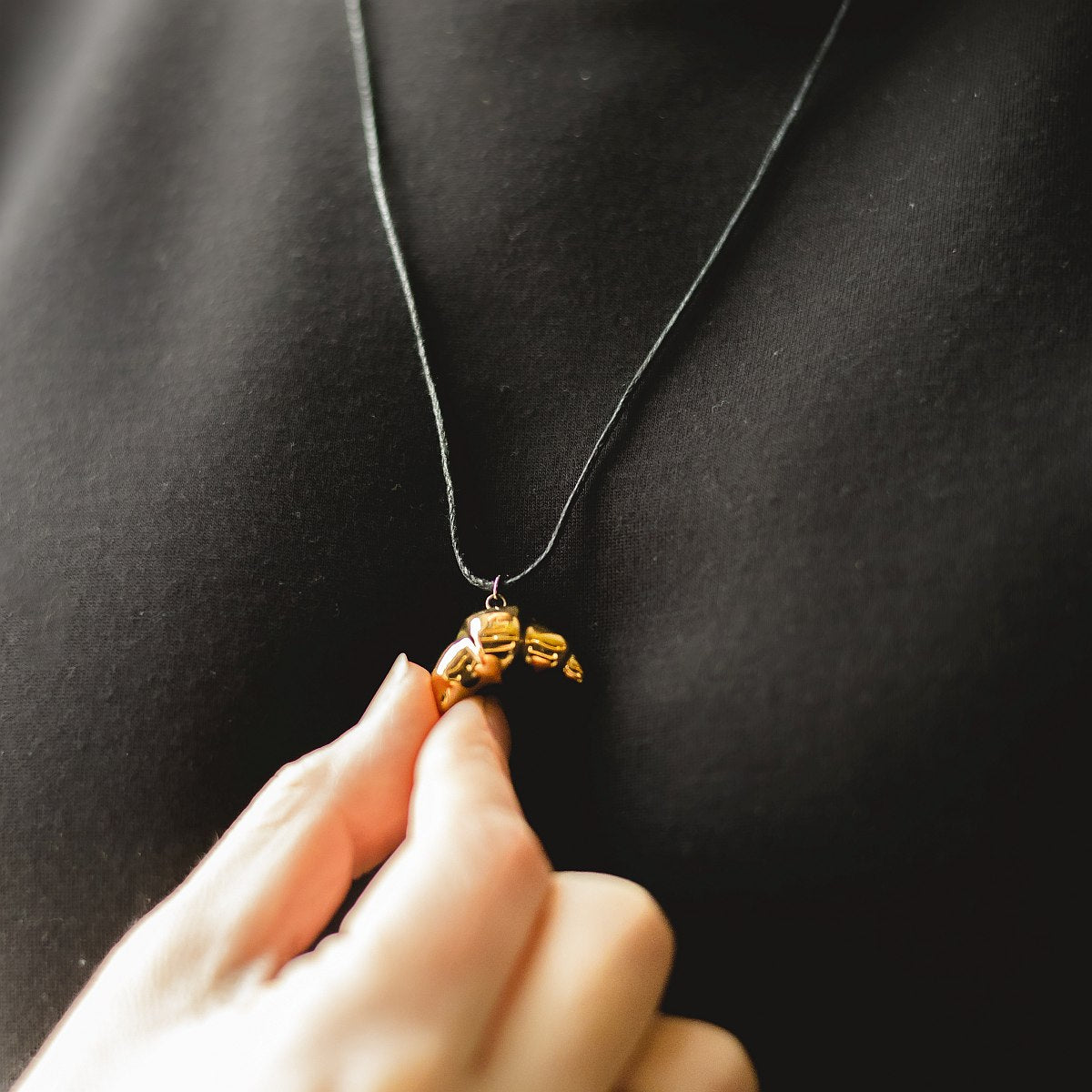 Handmade ceramic croissant pendant necklace with gold plated finish on black cord