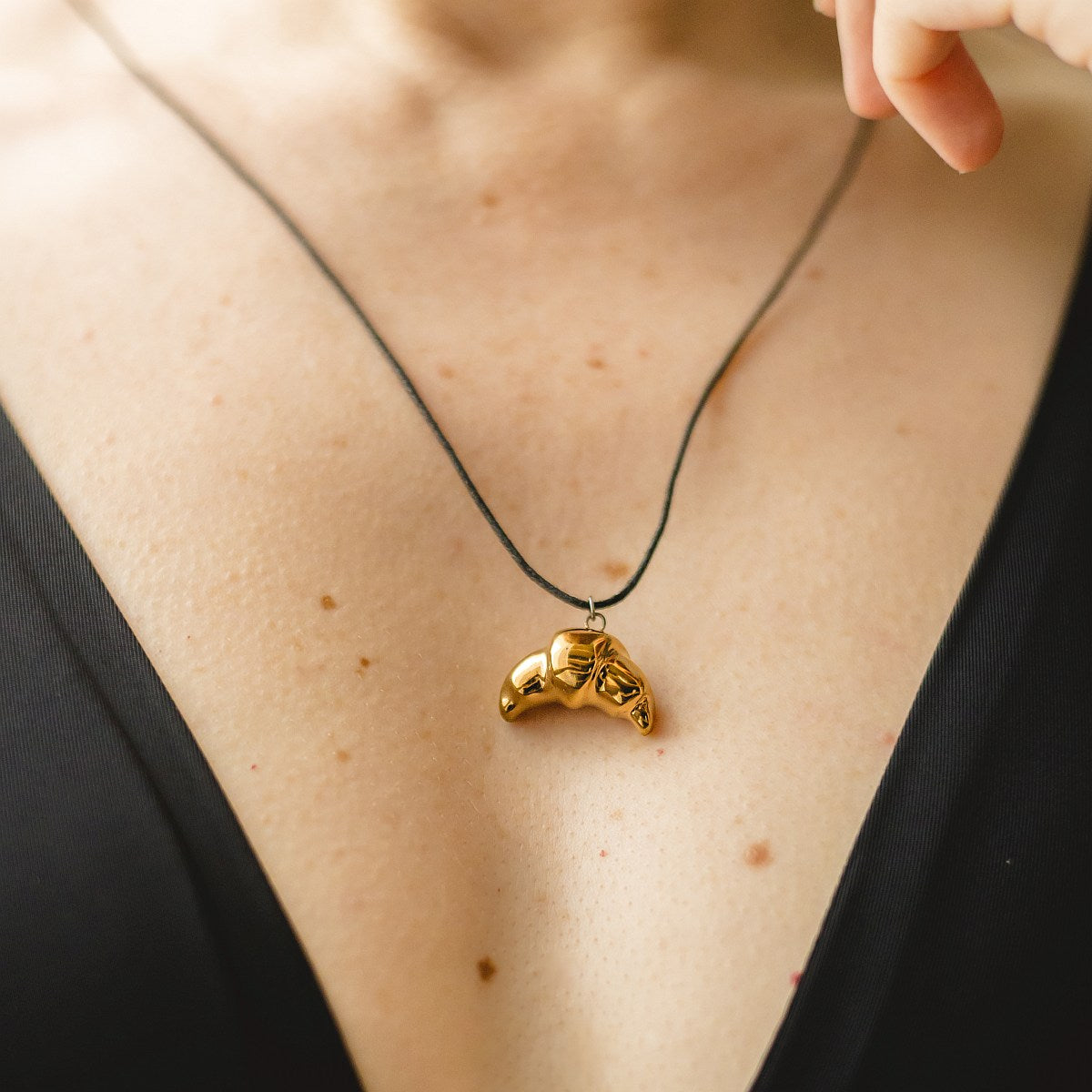 Handmade ceramic croissant pendant necklace with gold plated finish on black cord