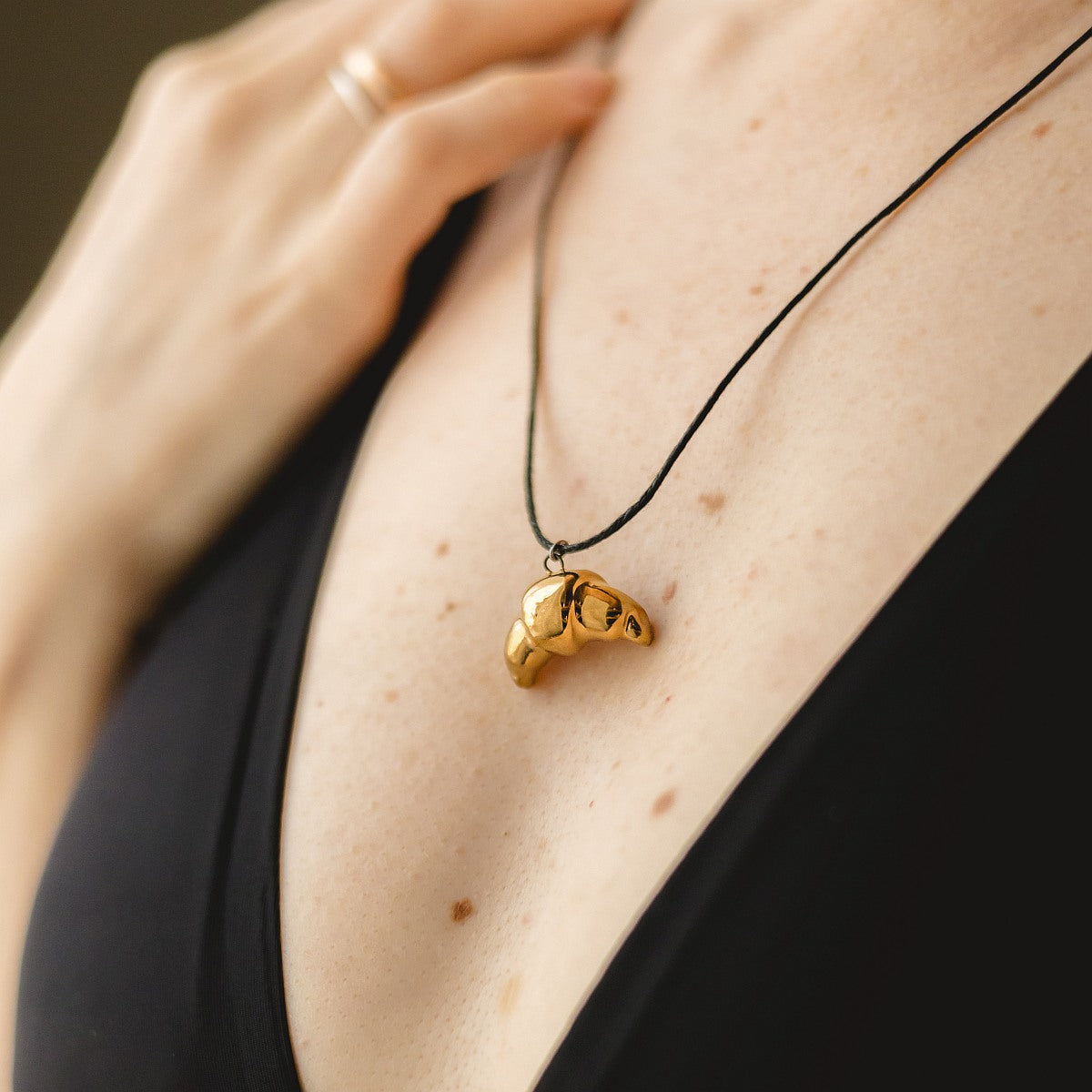 Handmade ceramic croissant pendant necklace with gold plated finish on black cord