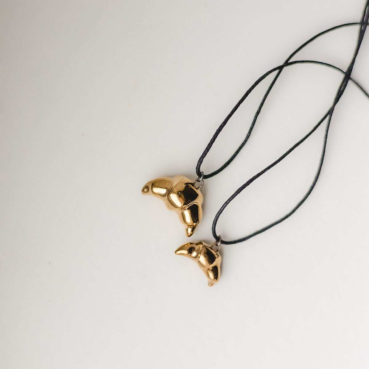 Handmade ceramic croissant pendant necklace with gold plated finish on black cord