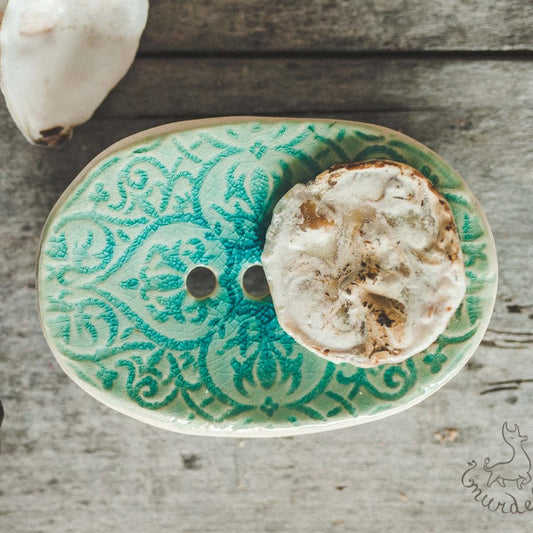 Handmade ceramic soap dish. Crafted from white clay and finished with a glossy light blue glaze. Designed with drainage holes, a concave shape, and four little feet.