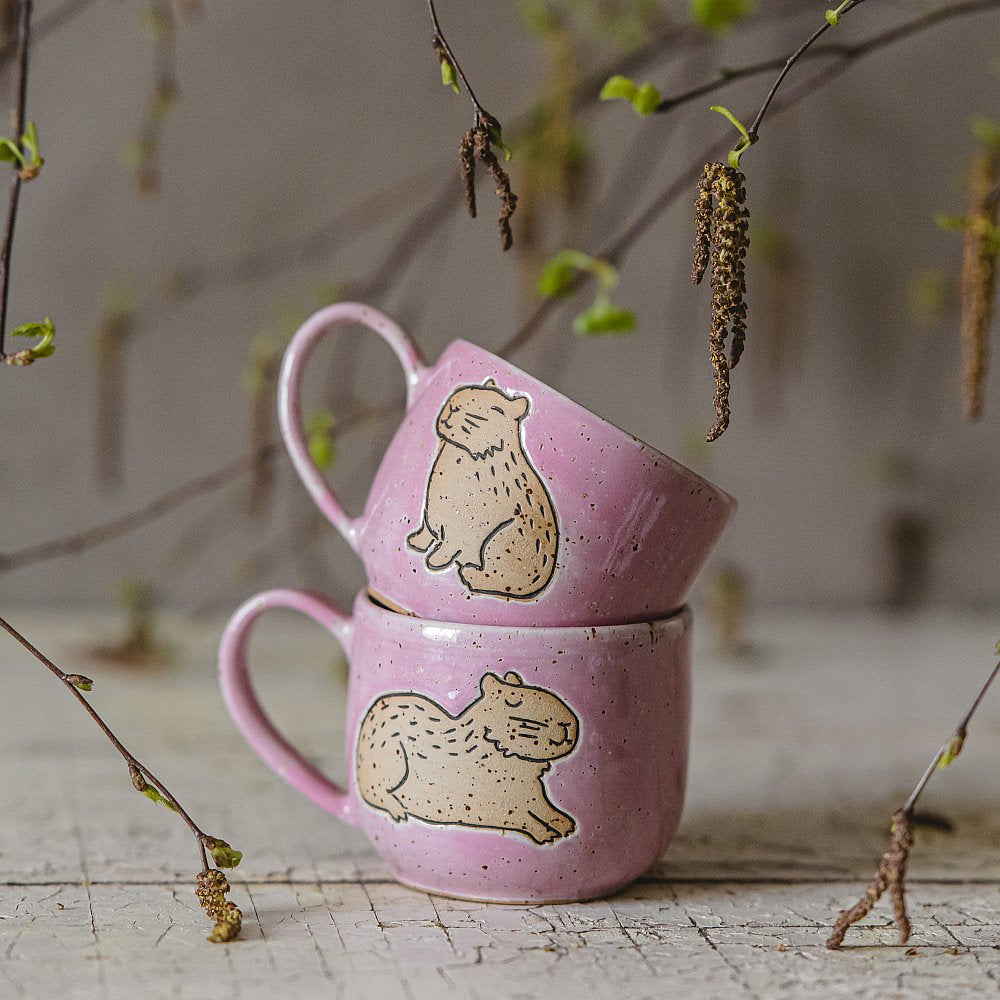 Handmade pink ceramic mug with a glossy glaze, featuring an unglazed capybara design on the side.