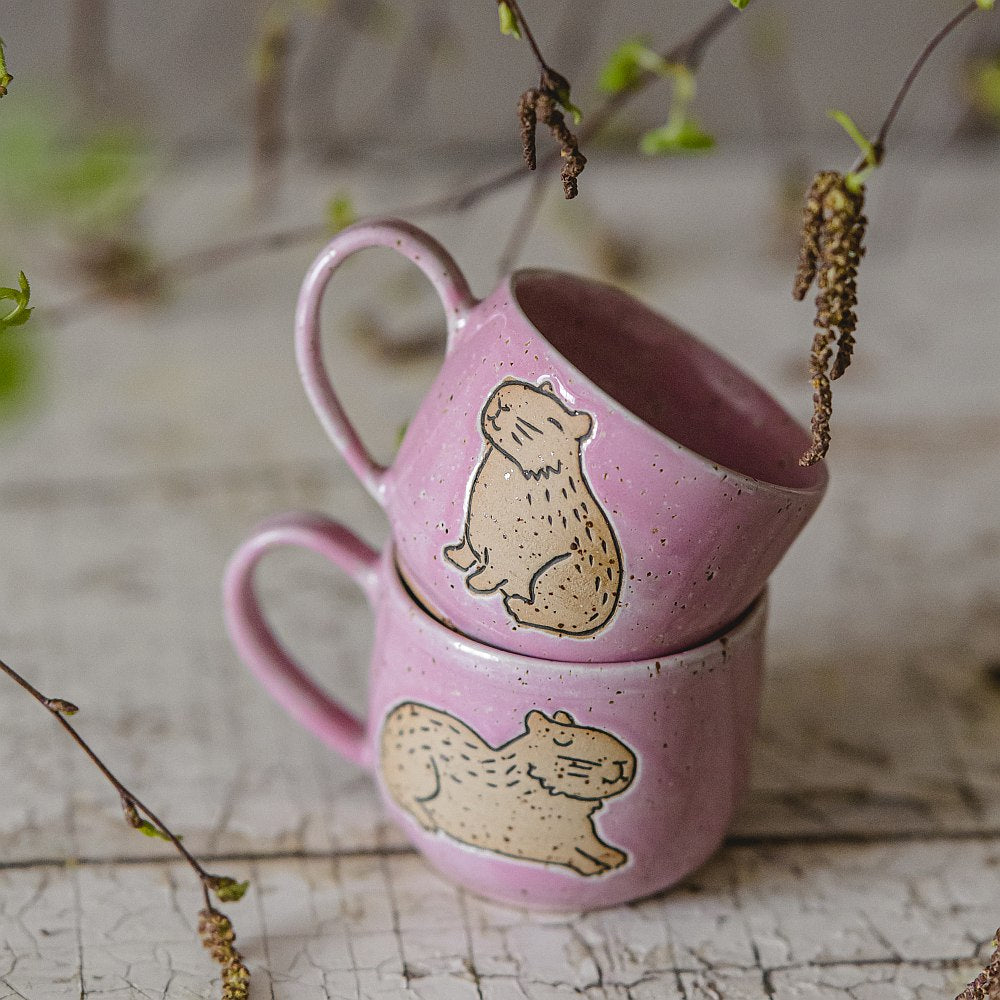 Handmade pink ceramic mug with a glossy glaze, featuring an unglazed capybara design on the side.