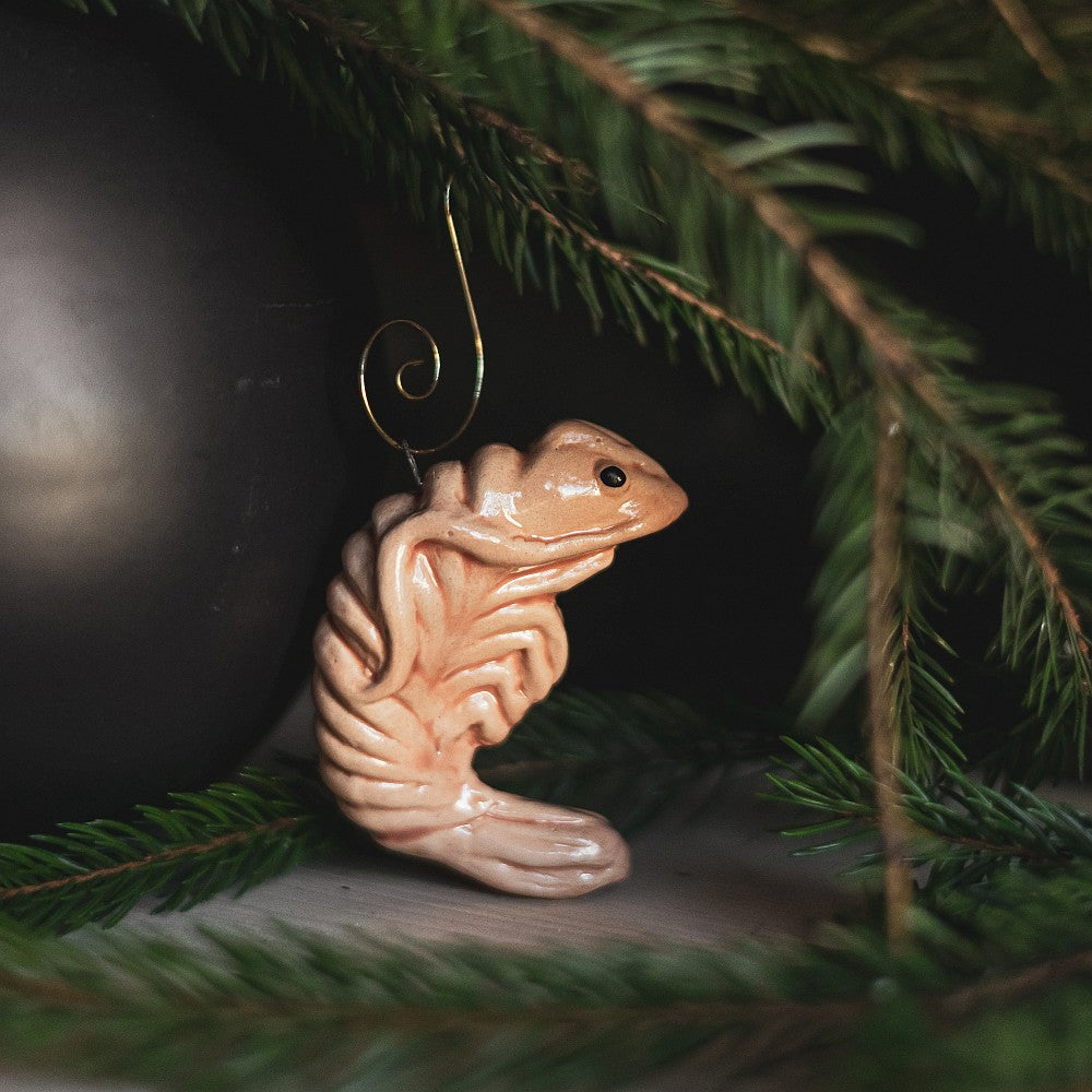 A ceramic pink shrimp ornament with black eyes. The decoration is handmade and comes with yellow hook.