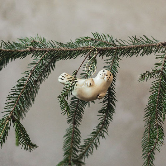 A ceramic seal ornament with black painted eyes, nose and tail. The decoration is handmade and comes with yellow hook.