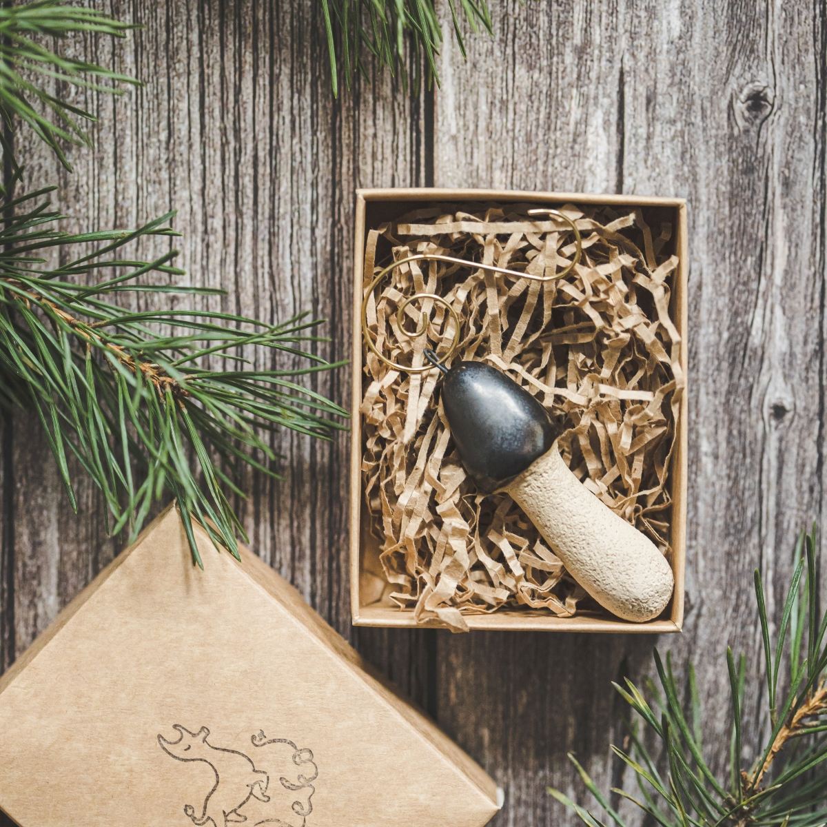Ceramic stinkhorn mushroom with mat black cap and cream-colored stem. Handmade Christmas tree ornament with hook.