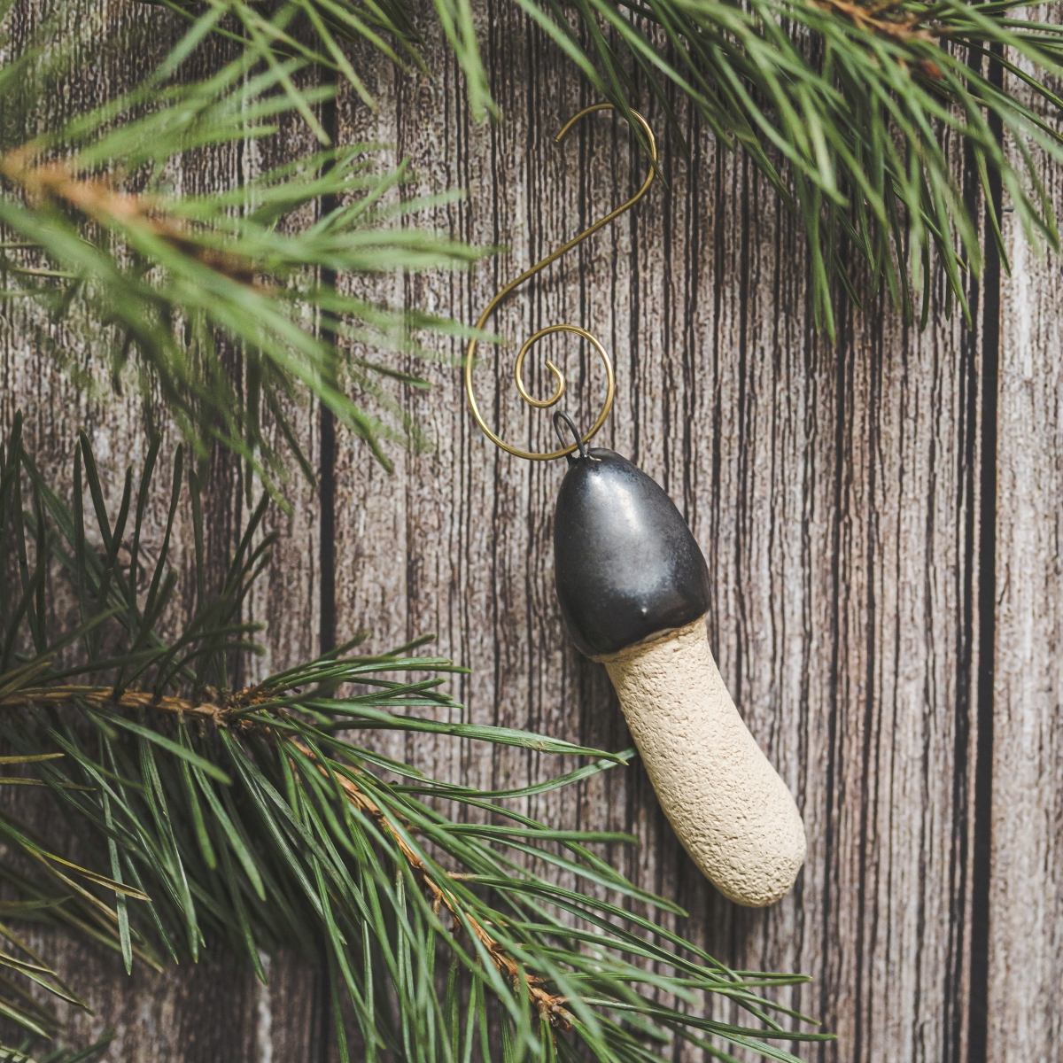 Ceramic stinkhorn mushroom with mat black cap and cream-colored stem. Handmade Christmas tree ornament with hook.