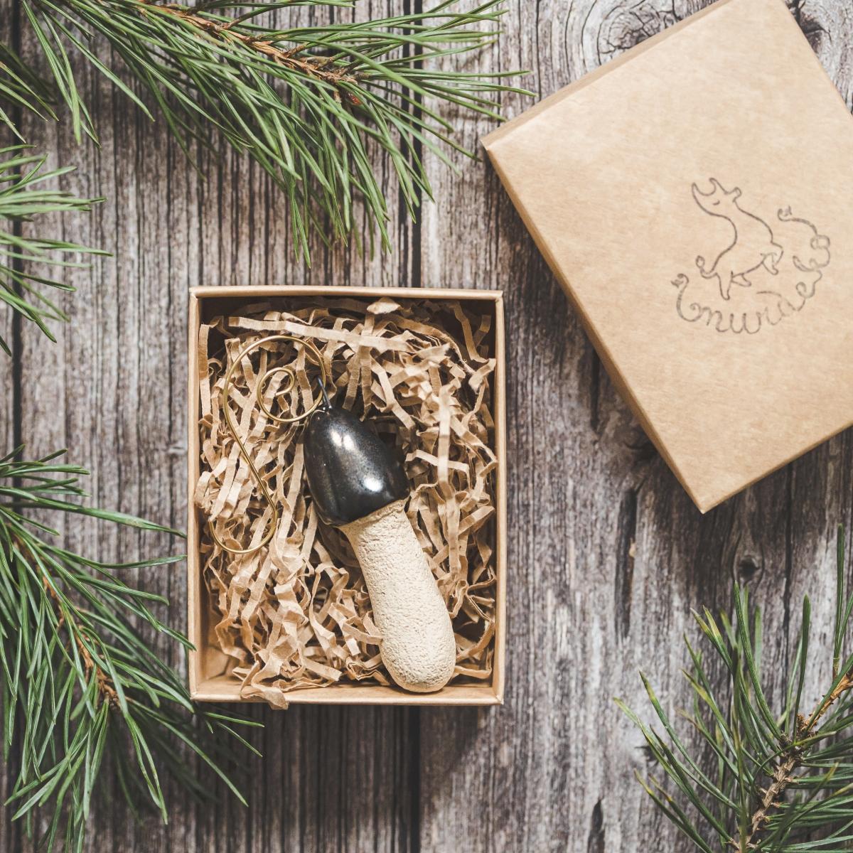 Ceramic stinkhorn mushroom with mat black cap and cream-colored stem. Handmade Christmas tree ornament with hook.