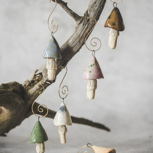 Christmas ornament set of six pastel blue, purple, brown, yellow, white and green swamp mushrooms. Hanging on a Christmas tree.