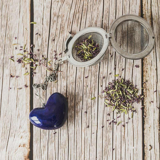 Tea infuser with ceramic blue heart hanging from the chain. Packed in a paper gift box.