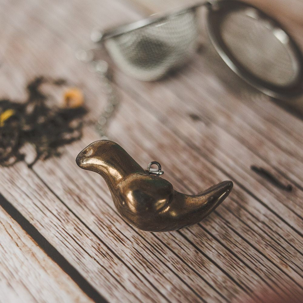 Tea infuser with ceramic bronze bird hanging from the chain.