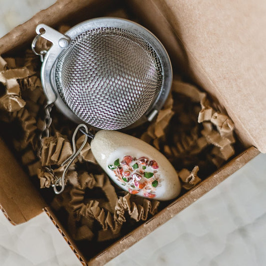 Stainless steel loose leaf tea infuser featuring a hand-made ceramic cepelinas (potato meat dumpling) charm hanging from the chain.