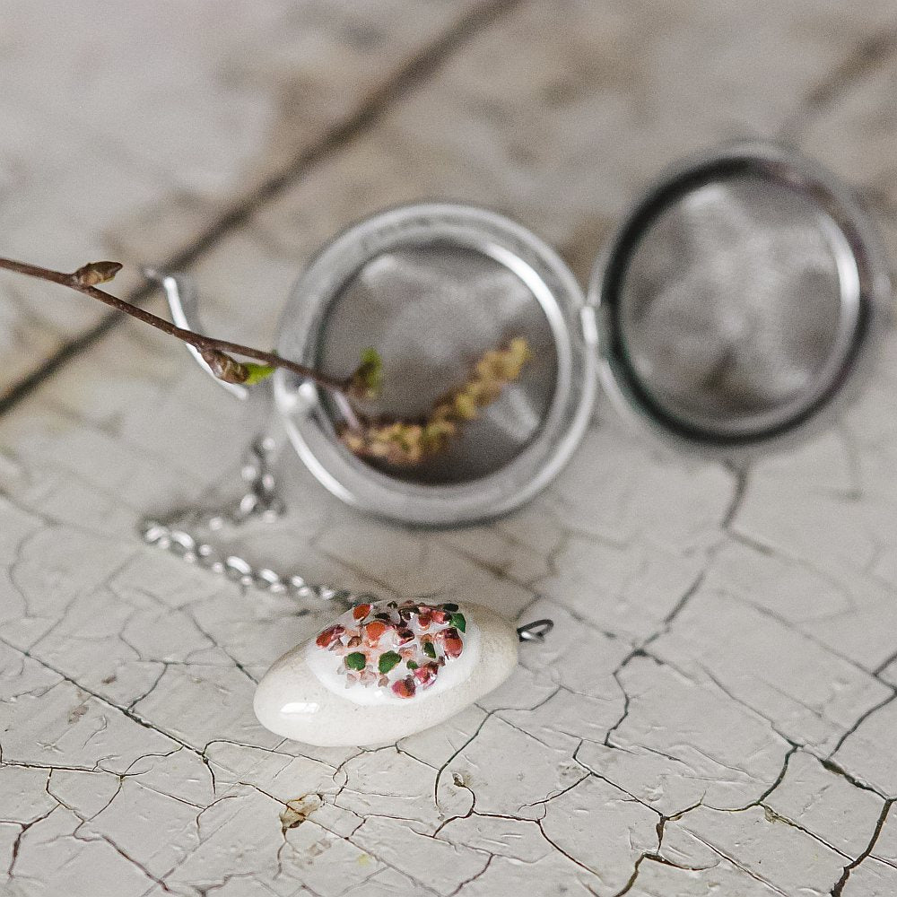 Stainless steel loose leaf tea infuser featuring a hand-made ceramic cepelinas (potato meat dumpling) charm hanging from the chain.