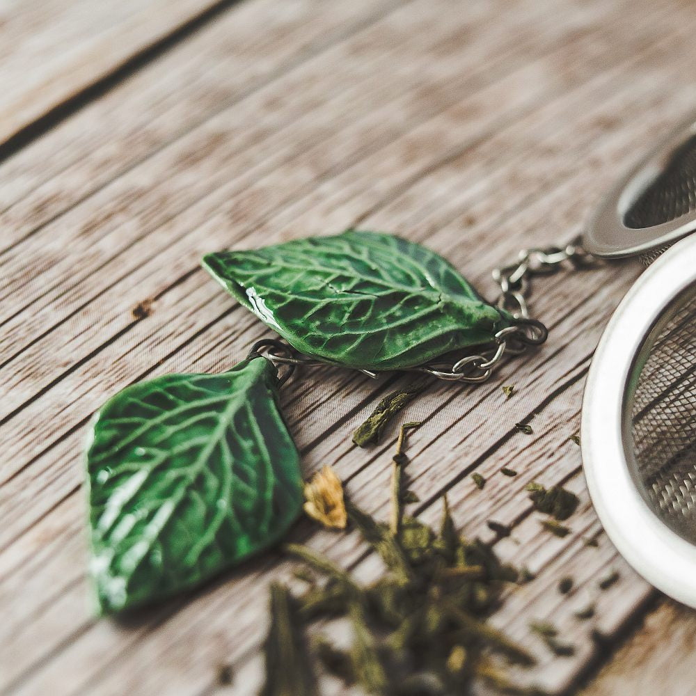 Tea infuser with ceramic green leaves hanging from the chain.