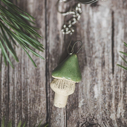 Tea infuser with ceramic green mushroom hanging from the chain.