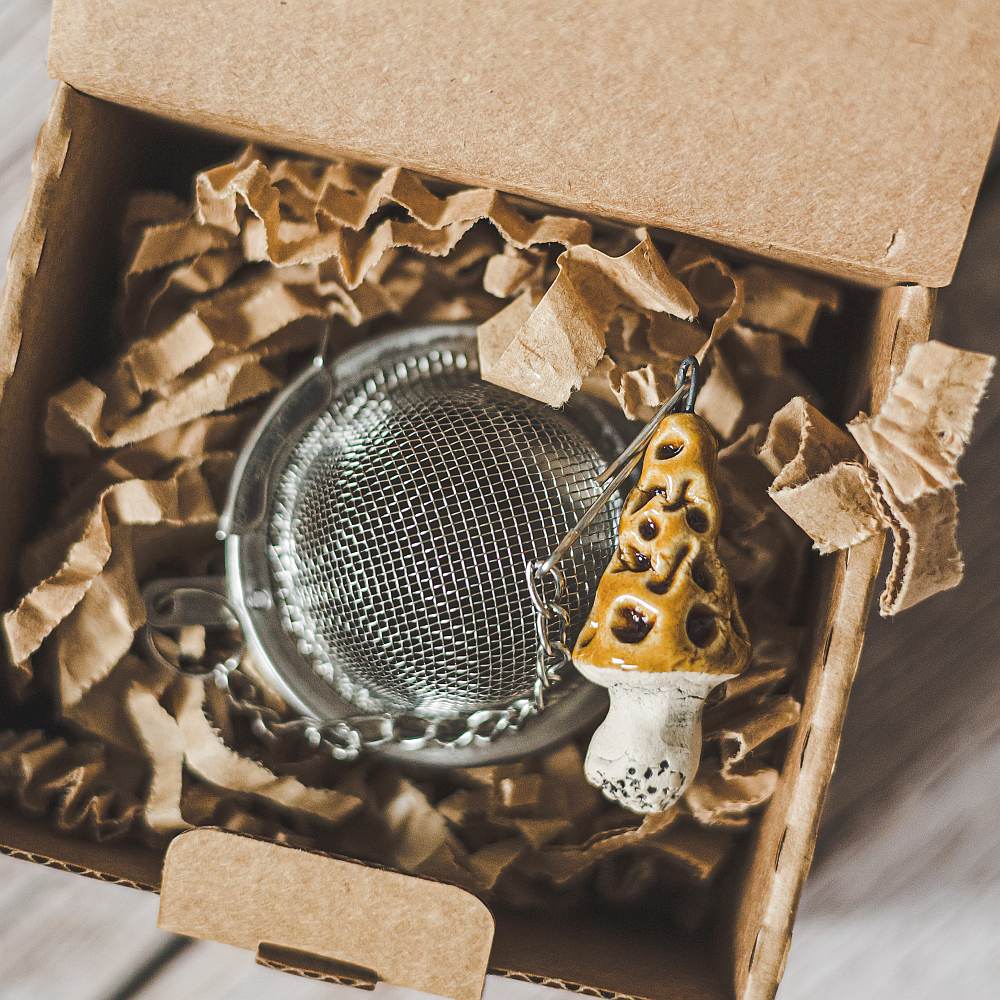 Tea infuser with ceramic gyromitra mushroom hanging from the chain. Packed in a paper gift box.